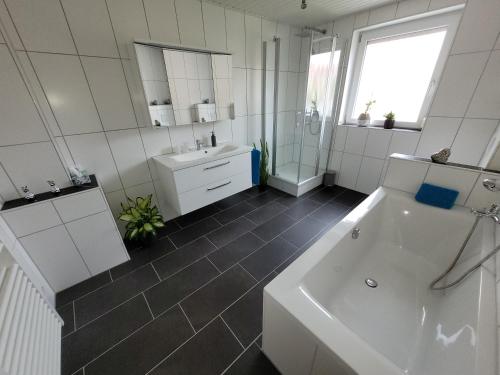 a white bathroom with a tub and a sink at Ferienwohnung Melanie Wackersdorf in Wackersdorf