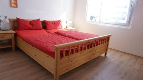 a bedroom with a wooden bed with red sheets and a window at Ferienhaus Sonnenstrahl in Meersburg