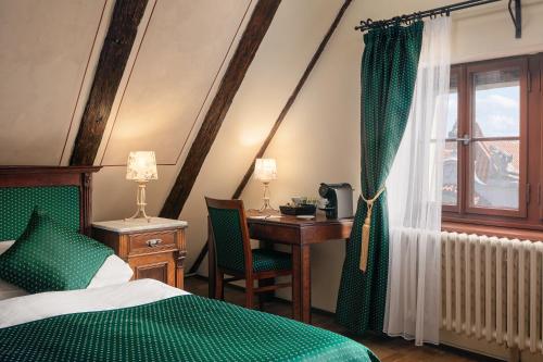 een slaapkamer met een bed, een bureau en een raam bij The Charles in Praag