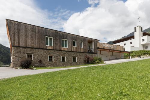 a large brick building with a white church at ArlBerglife Ferienresort in Pettneu am Arlberg