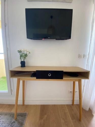 a wooden table with a television on a wall at La Sanary - Sleep in Sanary in Sanary-sur-Mer