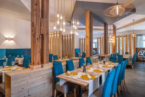 a dining room with wooden tables and blue chairs at Hotel Pejo in Peio Fonti