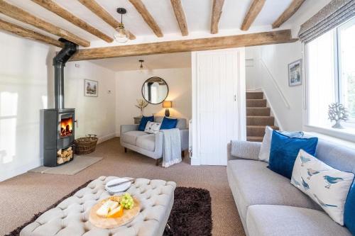 a living room with a couch and a fireplace at Laurel Cottage - Aldeburgh Coastal Cottages in Blyford