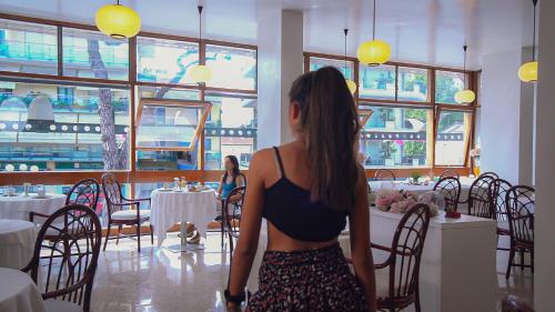 una donna seduta a un tavolo in un ristorante di Hotel Pinocchio a Cattolica