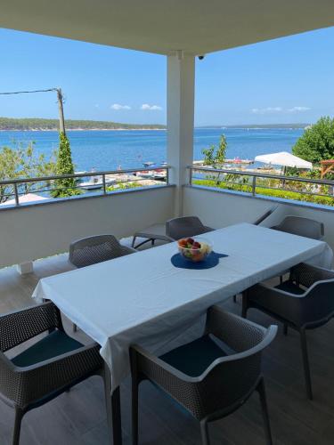un tavolo bianco e sedie su un balcone con vista sull'oceano di Villa Mali Apartments a Barbat na Rabu