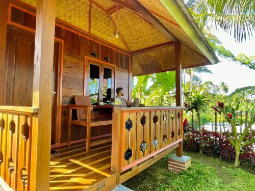 une femme assise à un bureau dans une maison en bois dans l'établissement Wina Wani Bungalows Tetebatu, à Tetebatu