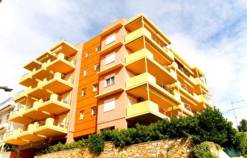 an orange apartment building with a stone wall at Dolphins Apartments in Loutra Edipsou