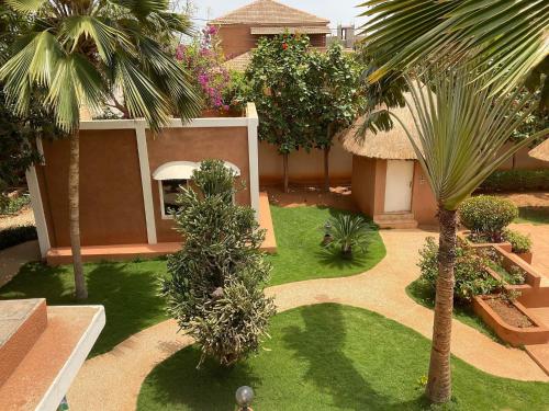a garden with a palm tree and a building at La Maison de Jeanne et Léa in Somone