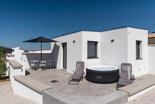 a patio with a hot tub and chairs and an umbrella at Casa Limoncino by Locap Group in Koper
