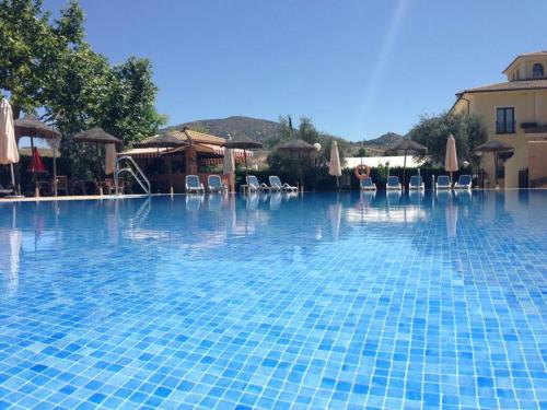 a large swimming pool with chairs and umbrellas at Hotel Rural Llano Piña in Loja