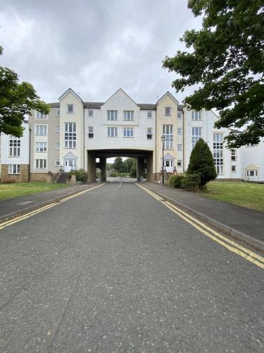 an empty road in front of a large white building at Pure Apartments Dunfermline East - Dalgety Bay in Saint Davids