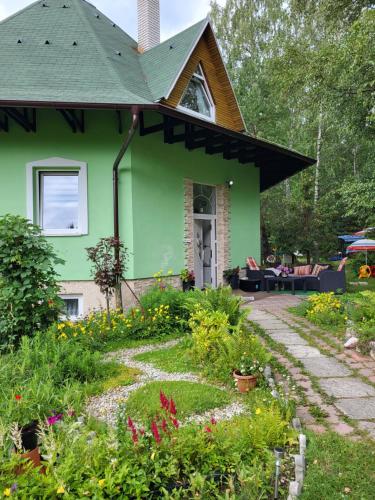 een groen huis met een tuin ervoor bij Vila Elena in Stará Lesná