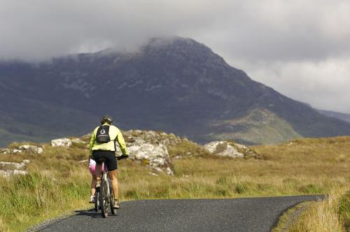 a person riding a bike on a road with a mountain at Apartment 432 - Clifden in Clifden
