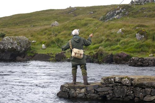 a man standing on a rock in a river fishing at Apartment 432 - Clifden in Clifden