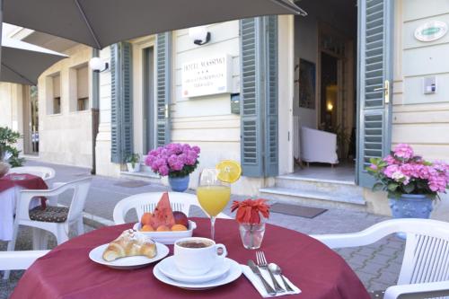 een tafel met een rode tafelkleed met eten en drinken bij Hotel Massimo in Viareggio
