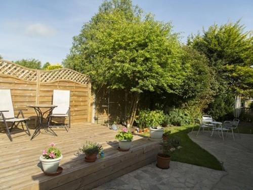 una terraza de madera con macetas, mesa y sillas en Bramlies Bed & Breakfast, en Dorchester