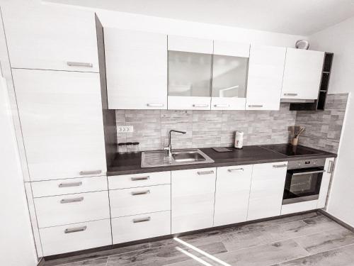 a kitchen with white cabinets and a sink at RIAD Apartments Premium in Zgornje Škofije