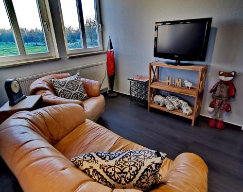 a living room with two couches and a flat screen tv at Ferienwohnung an der Barlter Mühle im ersten OG Nähe Nordsee in Barlt