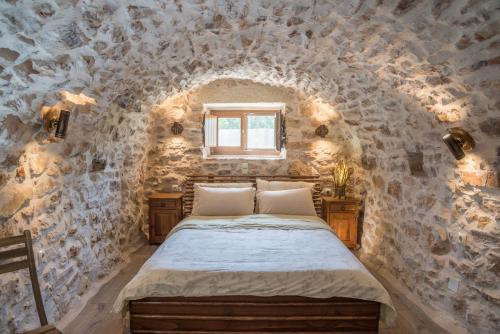 a bedroom with a bed in a stone wall at Karyoupolis Lounge Cave House in Gythio