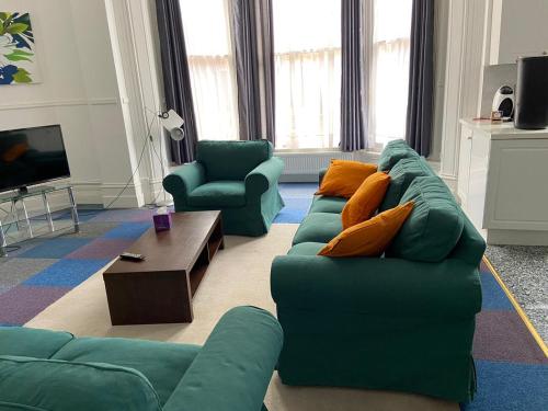 un soggiorno con un divano verde e 2 sedie di Gazeley Manor House - Central Huntingdon a Huntingdon