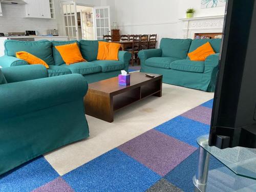 a living room with two blue couches and a coffee table at Gazeley Manor House - Central Huntingdon in Huntingdon