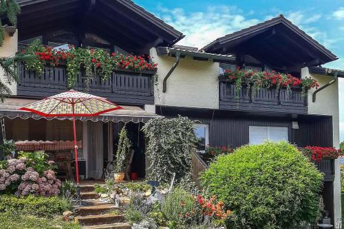 a house with flowering plants and an umbrella in front of it at Ferienwohnungen am Hasenweg in Ruhstorf