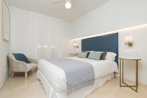 um quarto branco com uma cama grande e uma cadeira em iloftmalaga Martínez Maldonado em Málaga