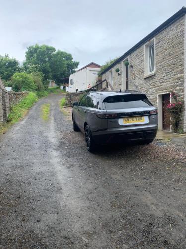 une voiture garée sur un chemin de terre à côté d'un bâtiment dans l'établissement Orkney Staycations - Thorvald, à Finstown