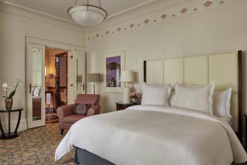 a bedroom with a large white bed and a chair at Four Seasons Hotel Gresham Palace Budapest in Budapest