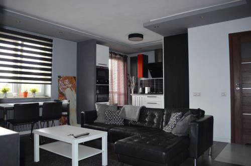 een woonkamer met een zwarte bank en een tafel bij Apartment in the City Center - FREE PARKING - easy check-in in Chorzów
