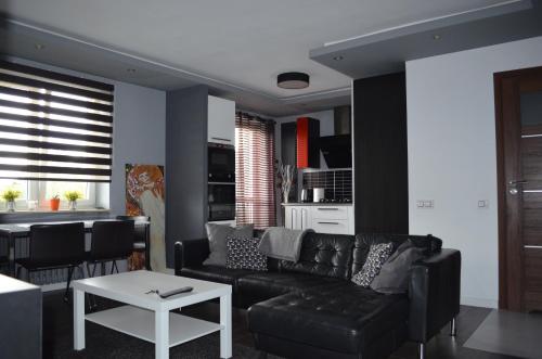 a living room with a black couch and a table at Apartment City Center - Free Parking - easy check-in in Chorzów