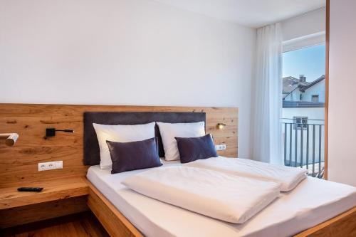 een slaapkamer met een bed met een houten hoofdeinde en een raam bij Luisl Hof - Apartment Vinum in Cornaiano