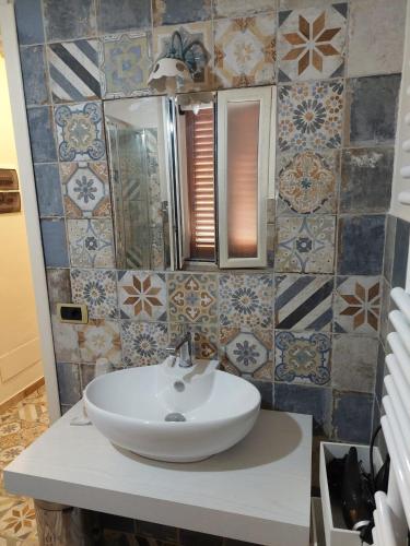 bagno con lavandino, specchio e piastrelle di Casa Petra a Castellabate