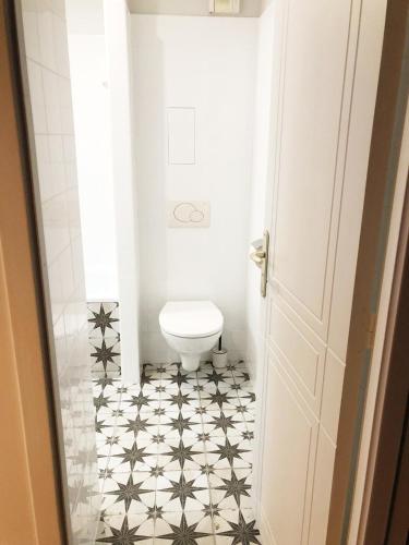 La salle de bains est pourvue de toilettes et de carrelage noir et blanc. dans l'établissement So Paris Group - Fully Serviced Studio Apartment - Jardin des Plantes - Heart of Paris, à Paris