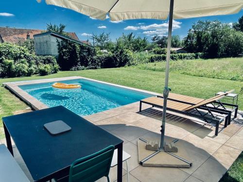 a swimming pool with an umbrella and a table and a picnic table at le Couvent des Climats in Corgoloin