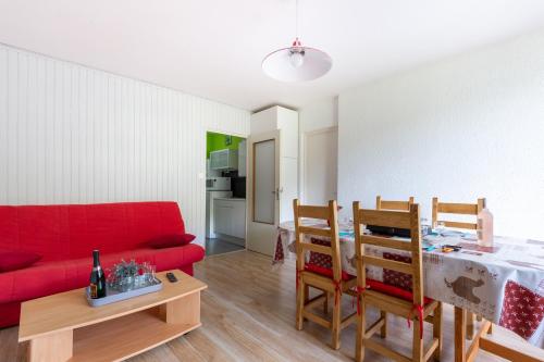 un salon avec un canapé rouge et une table dans l'établissement L'Ourson des Myrtilles, à La Bresse