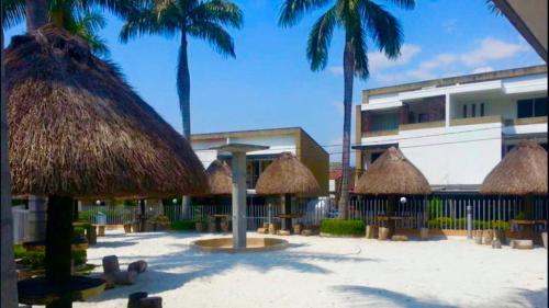 una spiaggia con alcuni ombrelloni di paglia e palme di CASA VACACIONAL CON PISCINAS EN SAN JERONIMO - CIUDADELA PREMIUm a Medellín