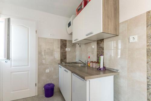 uma pequena cozinha com armários brancos e um lavatório em Apartments Markovic em Rogoznica