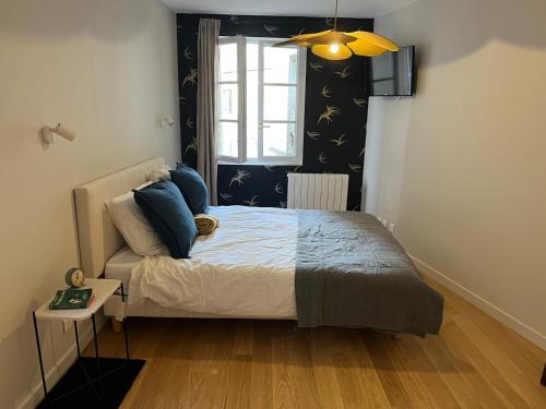 une chambre avec un lit avec des oreillers bleus et une fenêtre dans l'établissement So Paris Group - Fully Serviced Studio Apartment - Jardin des Plantes - Heart of Paris, à Paris