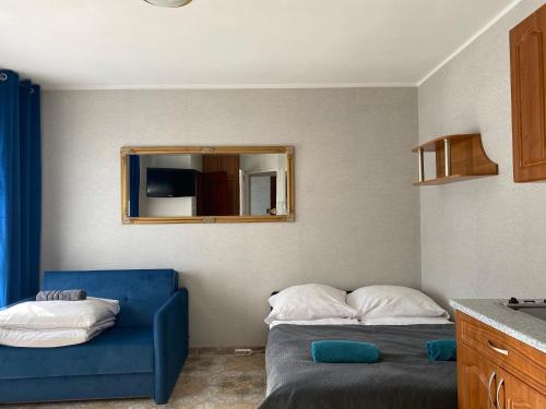a bedroom with a blue couch and a mirror at Twój Port in Krynica Morska