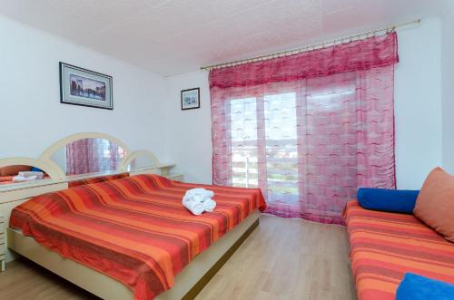 a bedroom with a bed and a couch and a window at Apartments Opsenica in Barbat na Rabu