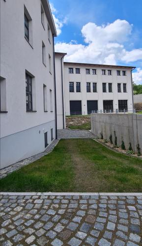 two white buildings next to a grassy yard next to a building at Loft Rezidence Kotel in Rokytnice nad Jizerou
