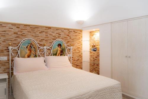 sypialnia z białym łóżkiem i ceglaną ścianą w obiekcie La Loggia del Buon Tempo w mieście Polignano a Mare