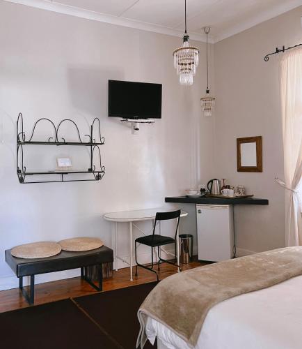 a bedroom with a table and a tv on the wall at Ebony Lodge in Mthatha