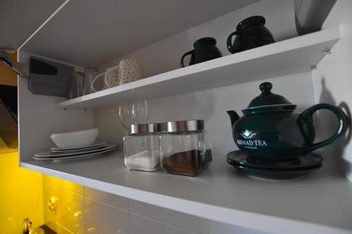 a kitchen shelf with dishes and a tea pot on it at APARTAMENTY T.R.11 Apartament nr 3 in Olsztyn