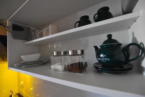 a kitchen shelf with dishes and a tea pot on it at APARTAMENTY TR 11 Apartament nr 3 in Olsztyn