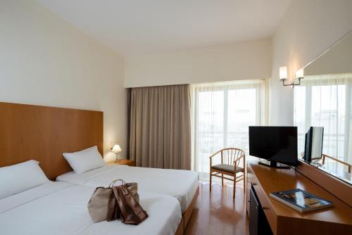 a hotel room with a bed and a desk with a television at Angela Downtown Hotel in Rhodes Town