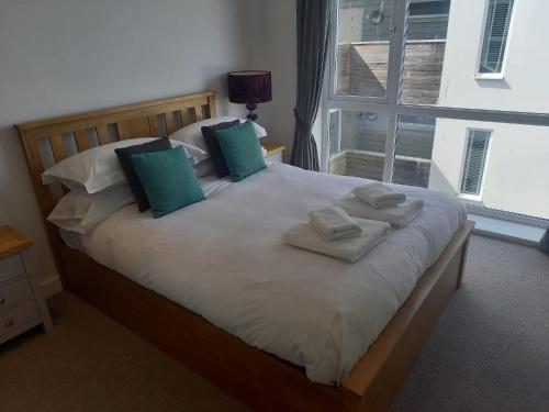een slaapkamer met een groot bed met groene en witte kussens bij The Towan Lookout in Newquay