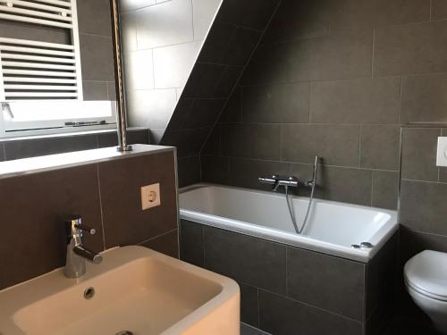 a bathroom with a tub and a toilet and a sink at Dorpsweg 18 nummer 7 in Callantsoog