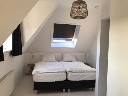 een slaapkamer met een bed op een zolder met een raam bij Dorpsweg 18 nummer 7 in Callantsoog